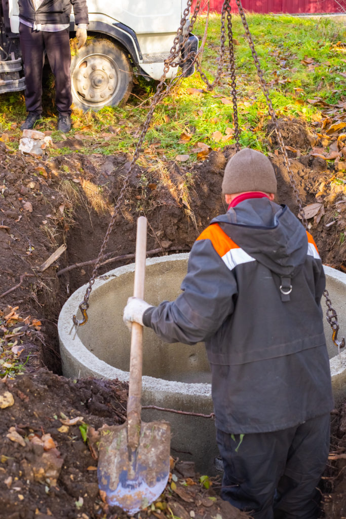 Technician carrying a shovel while inspecting a septic tank